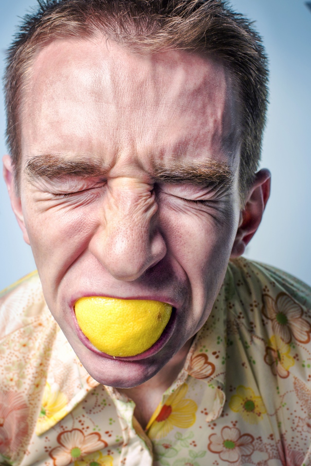 Мужчина с закрытыми глазами ест лимон 