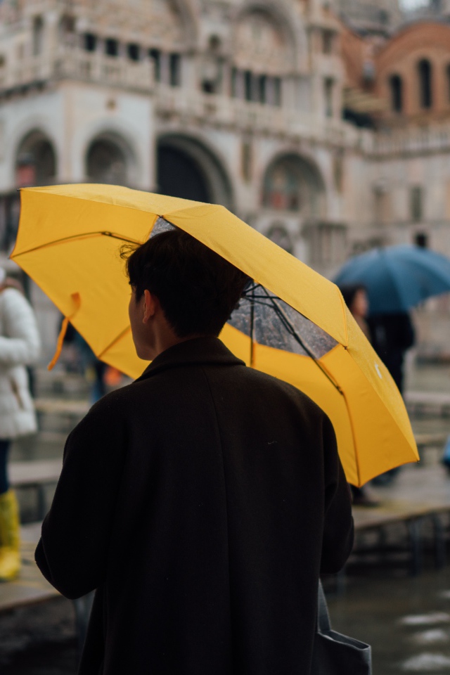 Мужчина с желтым зонтом в городе 