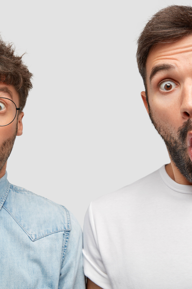 Два удивленных мужчины на сером фоне