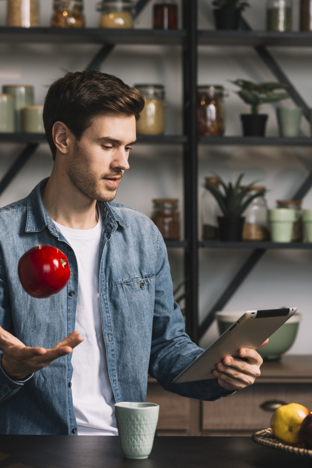 Молодой мужчина с планшетом и яблоком в руке 