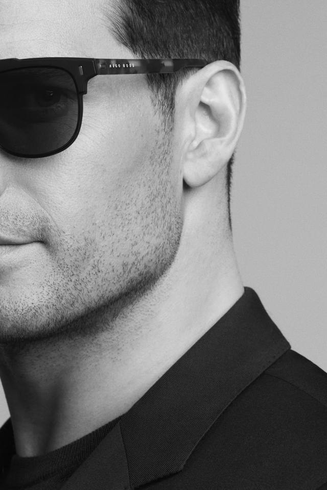 Актер Генри Кавилл в черных очках на сером фоне