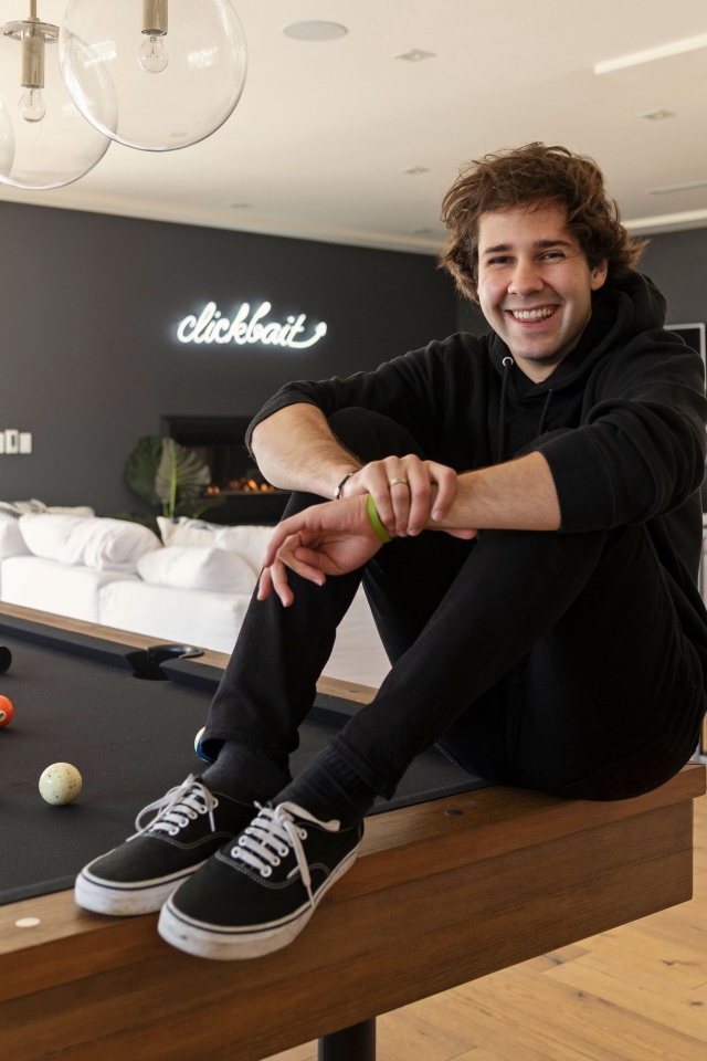 Молодой блогер, юморист  Дэвид Добрик сидит на столе