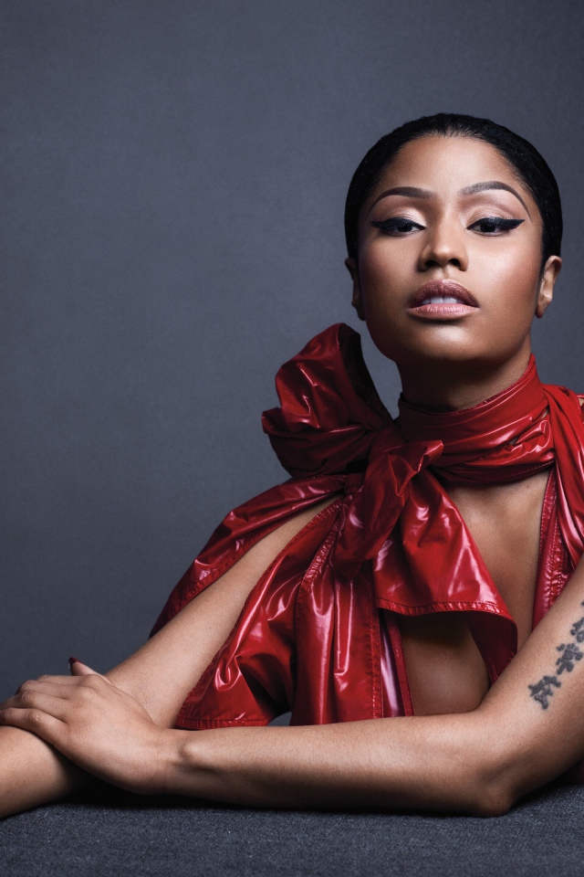 Американская певица, рэпер Ники Минаж  в красном наряде на сером фоне