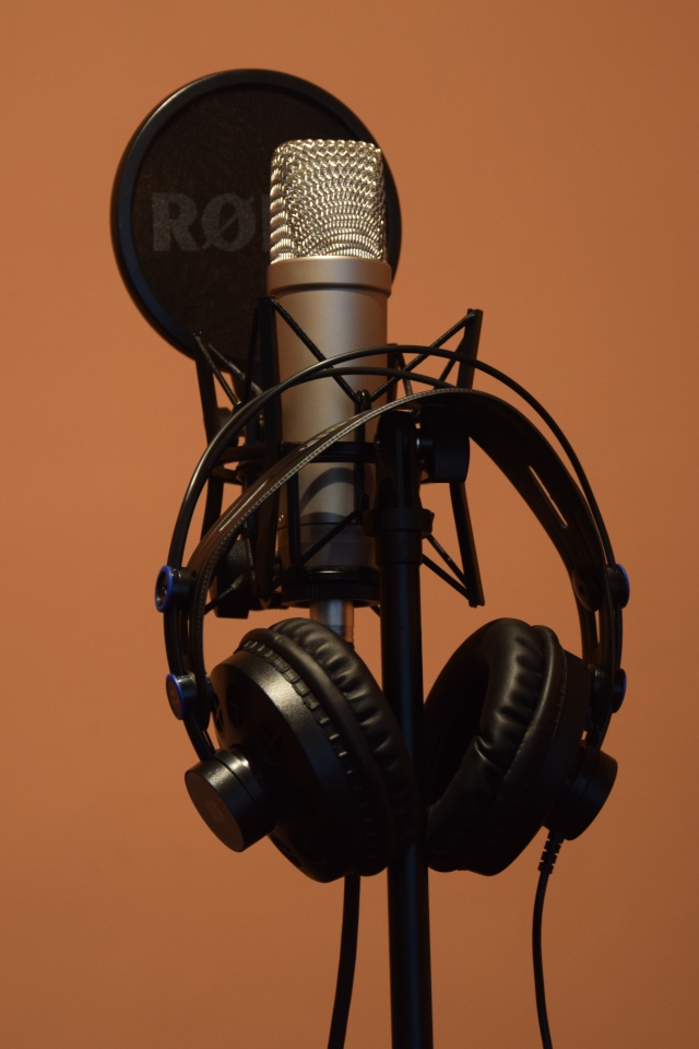 Condenser microphone with headphones on brown background