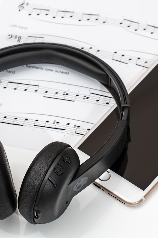 Наушники на столе с нотами и смартфоном
