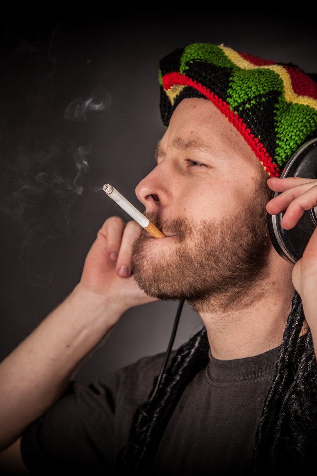 Мужчина растаман в наушниках с сигаретой 