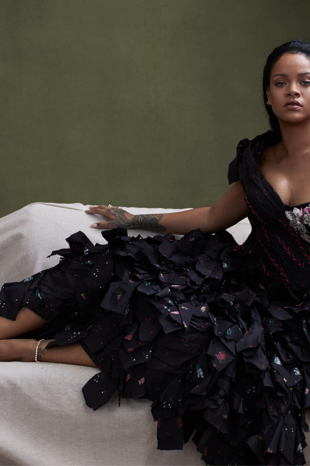 Певица Рианна в черном платье на диване 