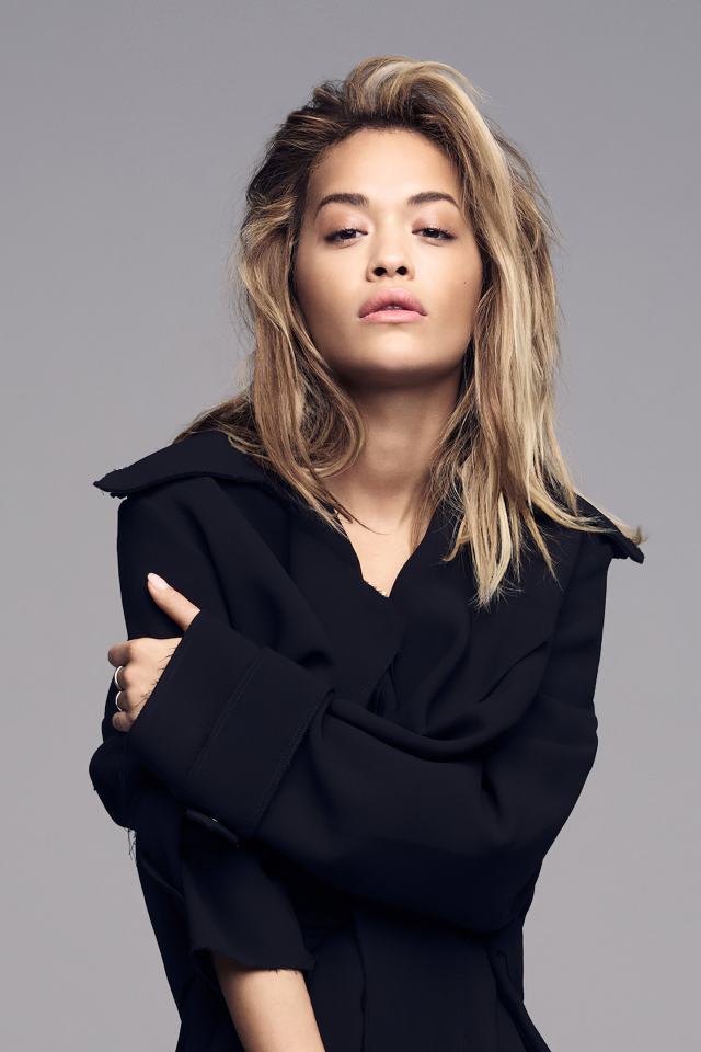 Певица Рита Ора в черном наряде на сером фоне