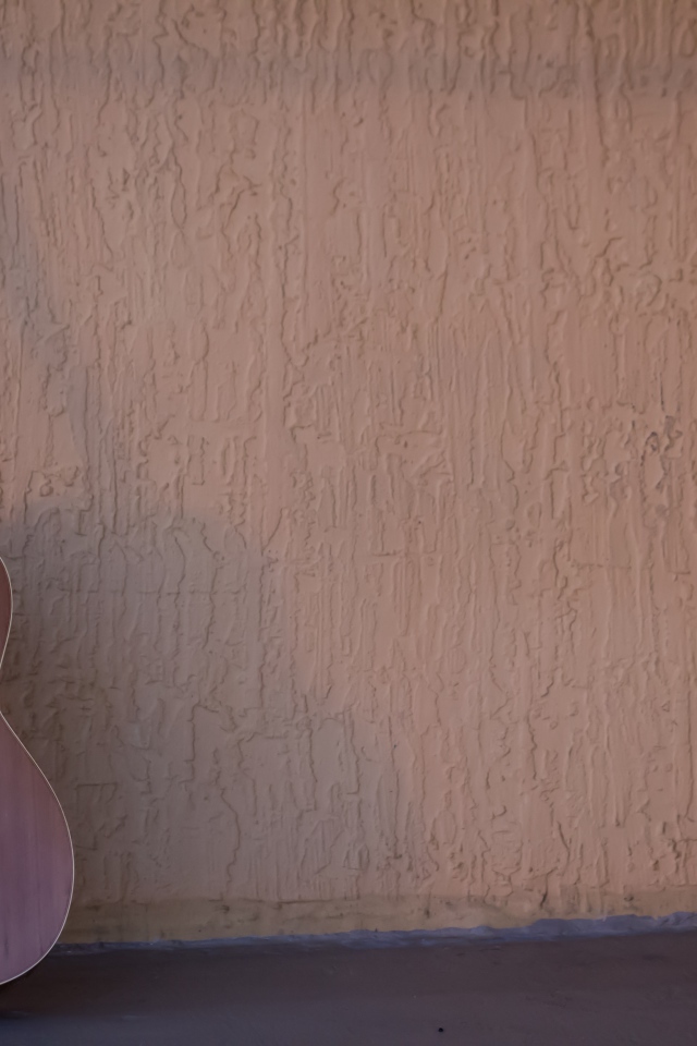 Шестиструнная гитара стоит у стены