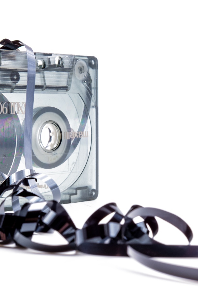 Магнитофонная кассета в размотанной пленкой на белом фоне