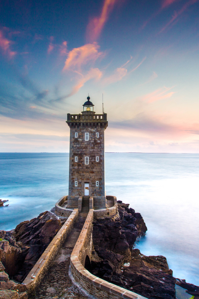 Большой маяк на фоне неба на берегу утеса 