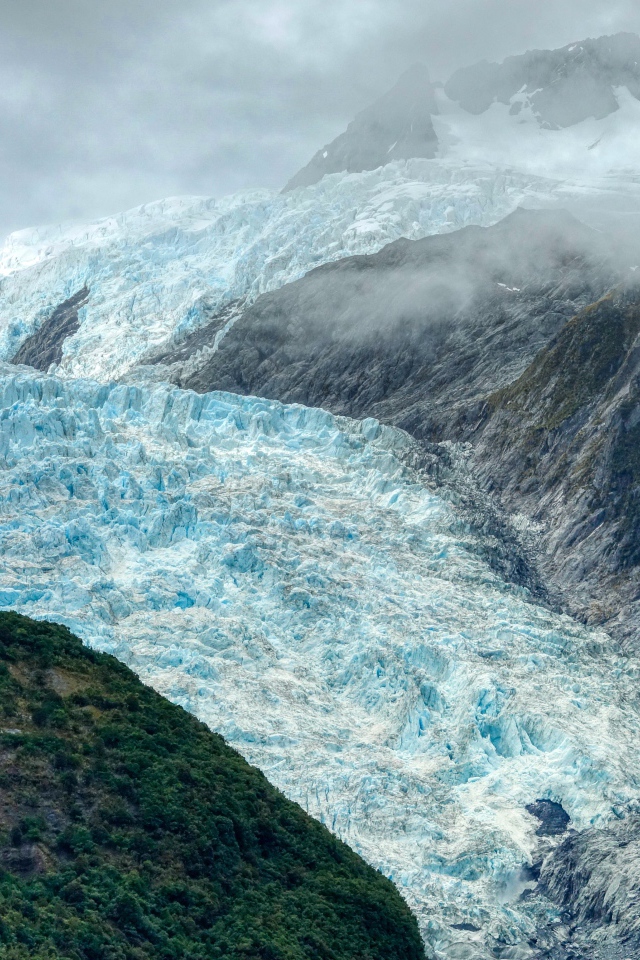 Голубой ледник между скал под грозовым небом