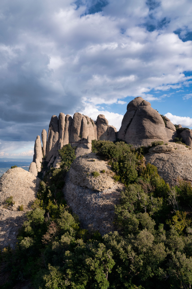 Каменные глыбы под голубым небом с грозовыми облаками 