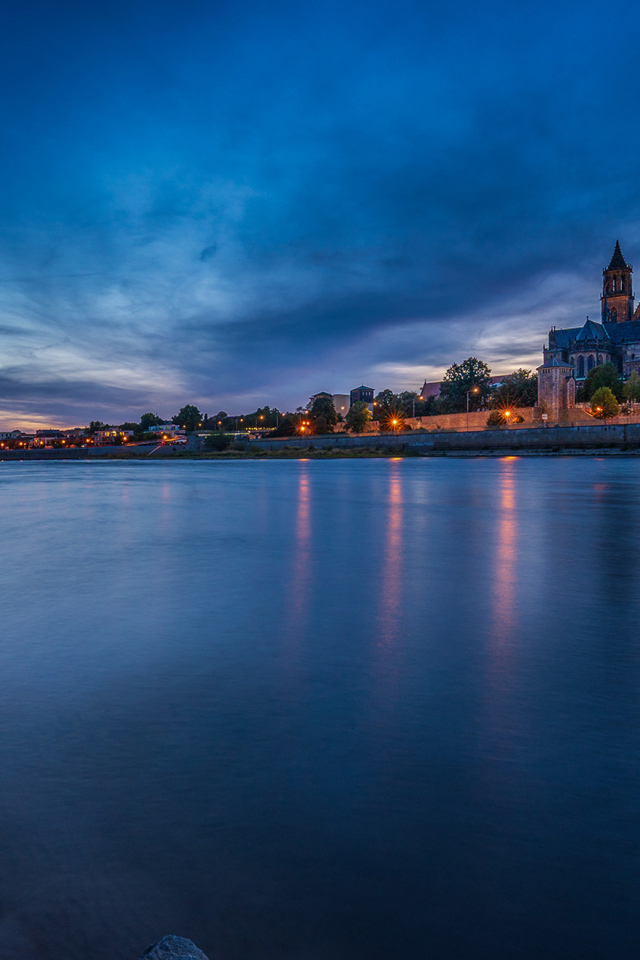 Замок у реки на фоне неба в сумерках 