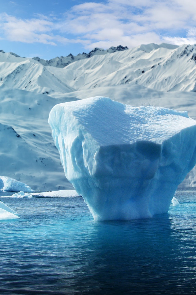 Большие глыбы льда в воде на фоне заснеженных гор 