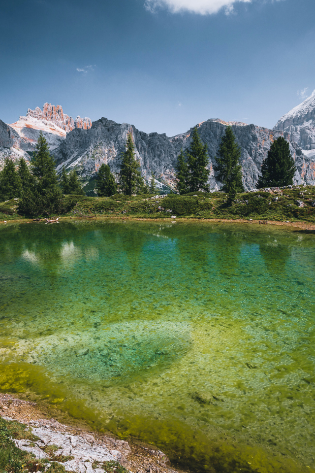 Озеро у заснеженных гор под небом с белыми облаками