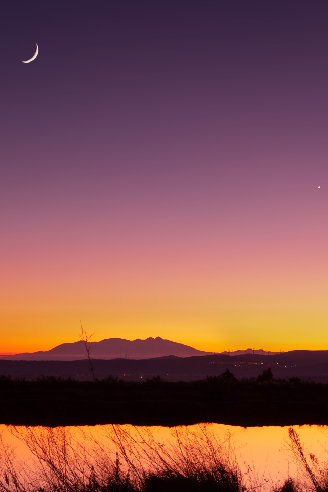 Молодой месяц в небе над озером ночью 