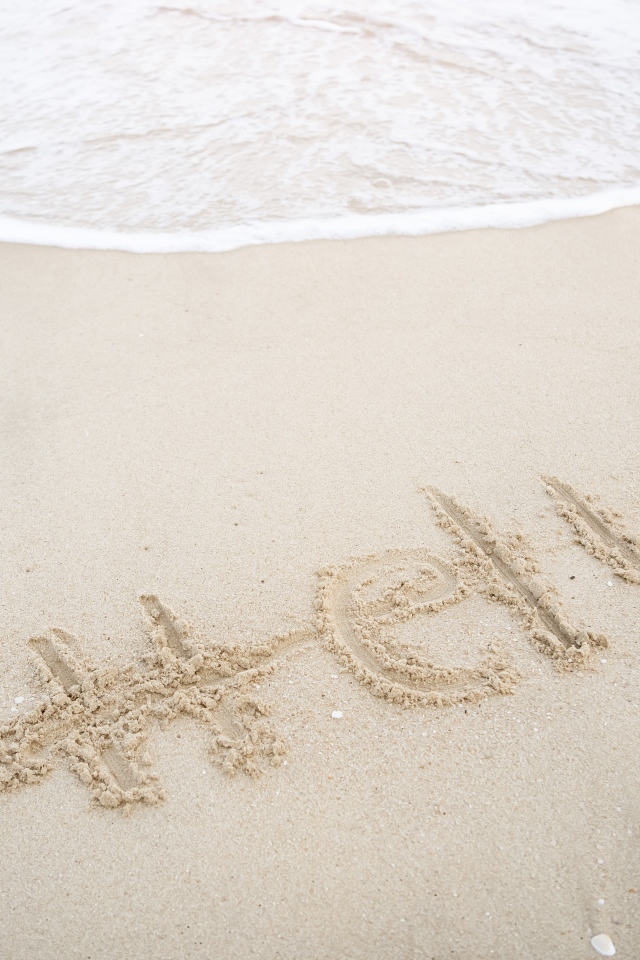 Надпись Hello на мокром песке у моря летом 