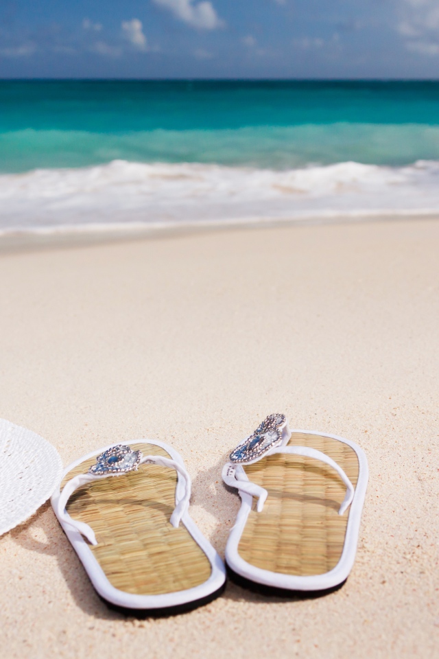 Сланцы, шляпа и ракушка на песке у моря 