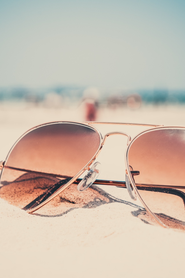 Солнечные очки лежат на горячем песке 
