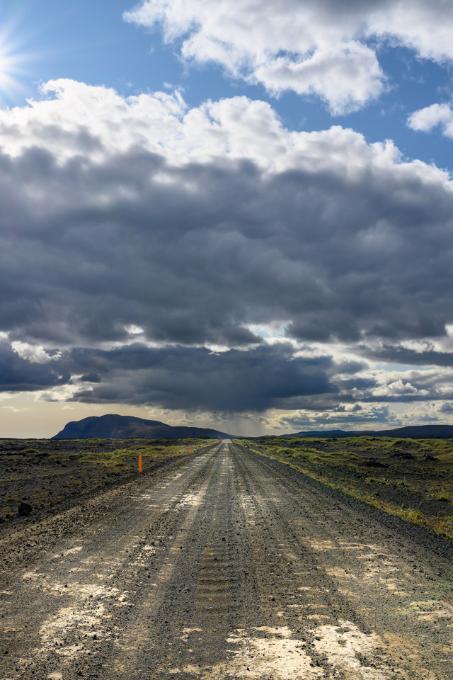 Длинная дорога под голубым солнечным небом с белыми облаками летом