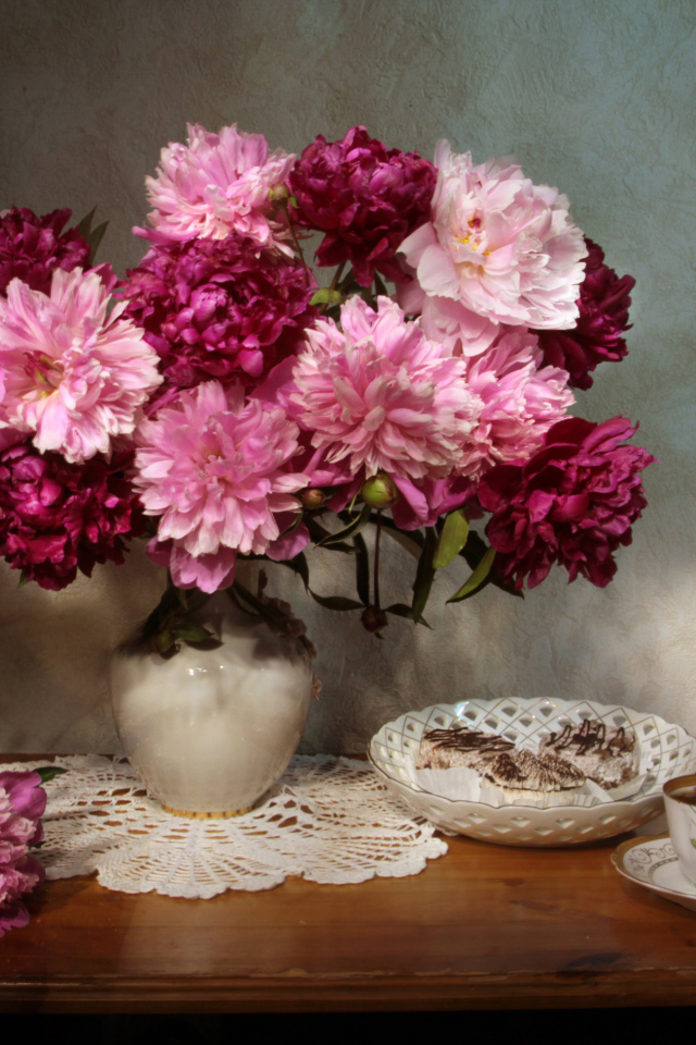 Большой букет розовых пионов в вазе на столе 