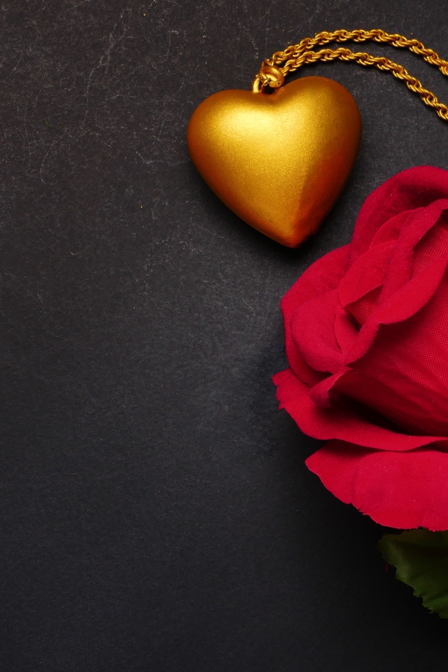 Искусственная красная роза с кулоном на сером фоне