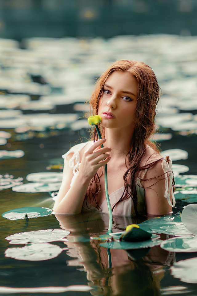 Красивая молодая девушка с водяными лилиями в пруду