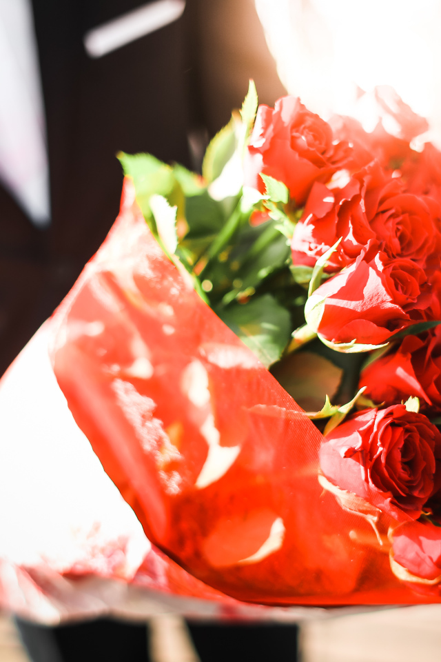 Большой красивый букет красных роз в руках мужчины 