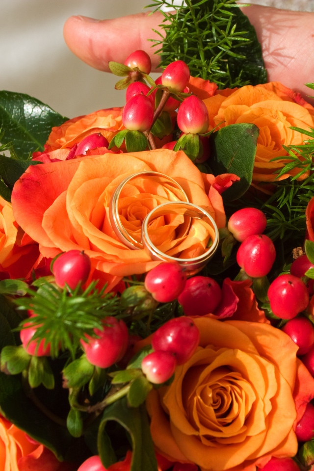Букет оранжевых роз с красными ягодами и обручальными кольцами