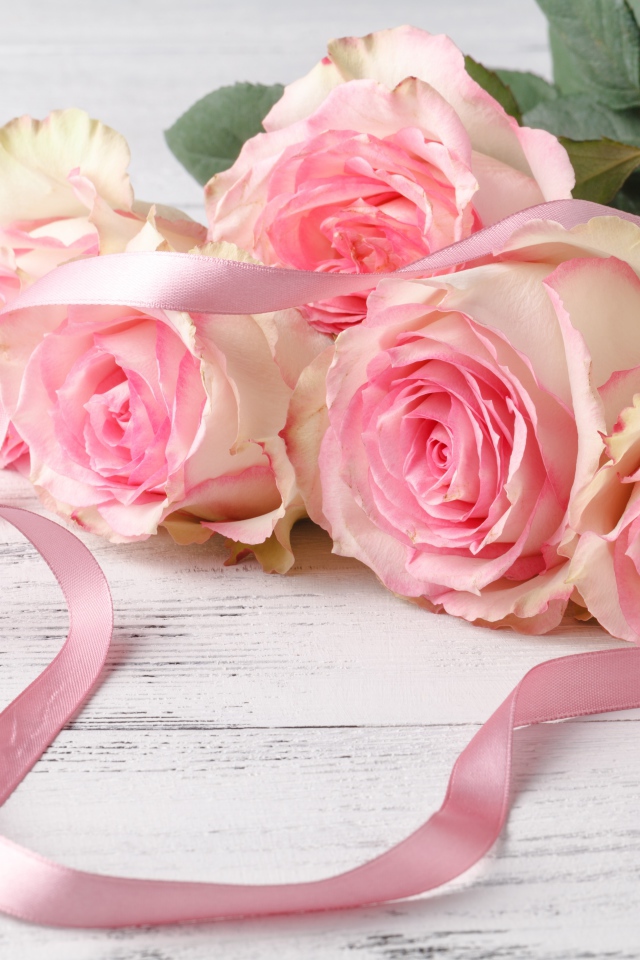 Букет розовых роз с лентой на белом столе 