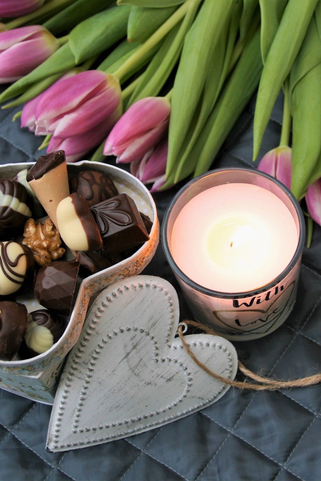 Букет розовых тюльпанов на кровати со свечой и коробкой конфет