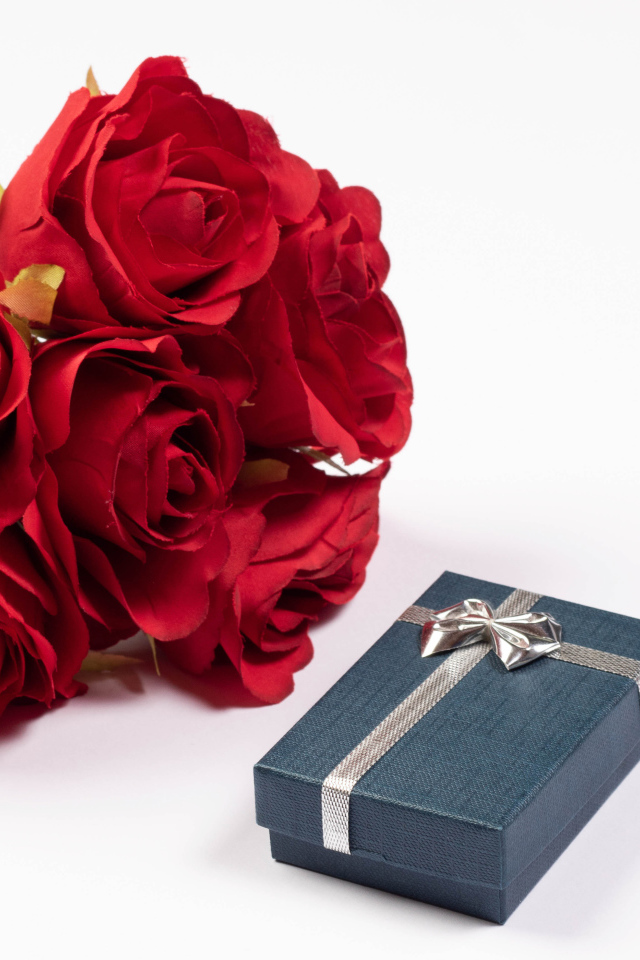 Букет красных искусственных роз с подарком на белом фоне
