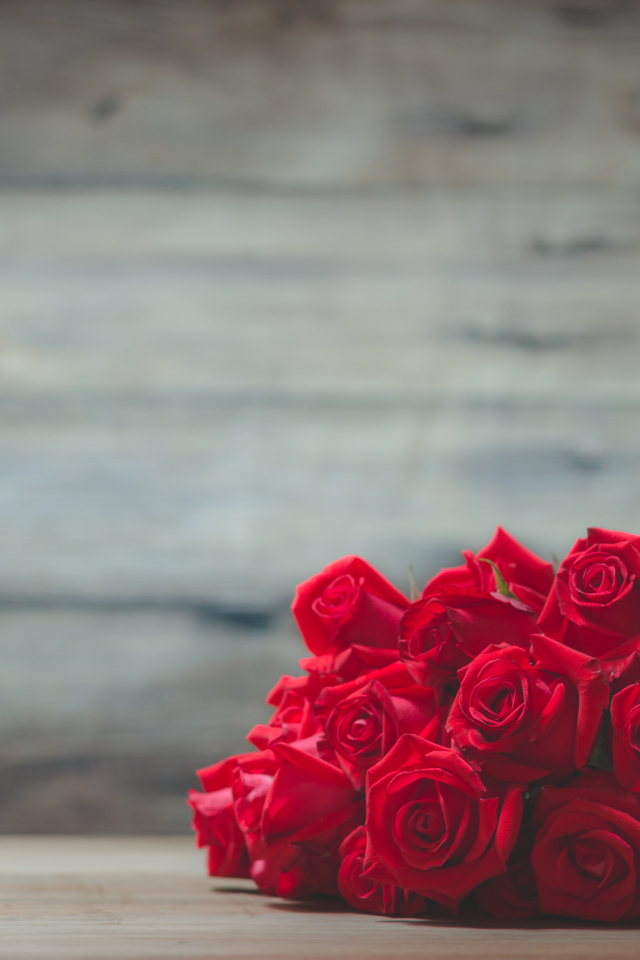 Букет красных роз на фоне деревянной стены 