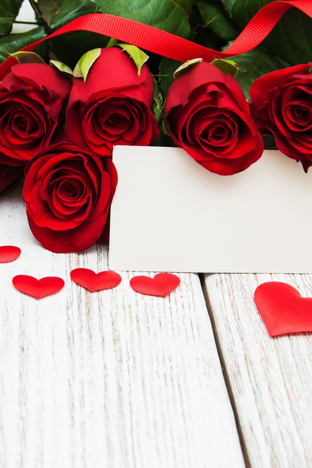 Букет красных роз на столе с сердечками и открыткой