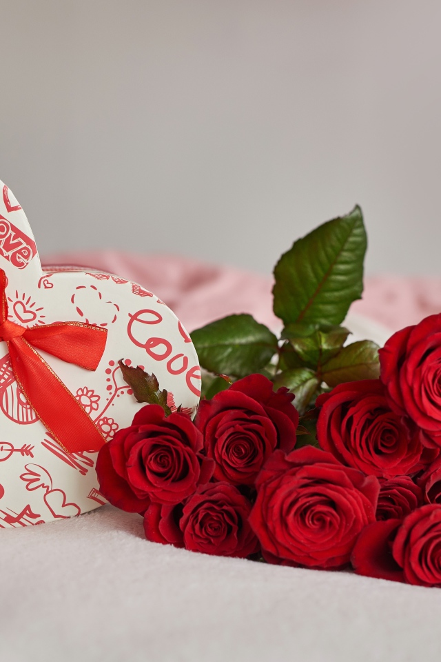 Букет красных роз с коробкой в форме сердца на кровати 