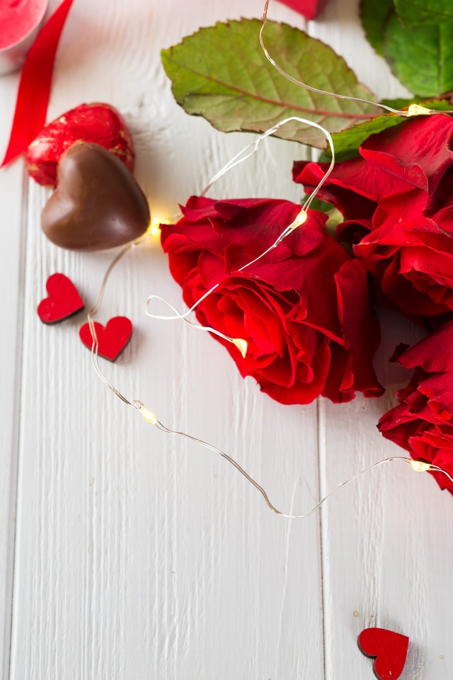 Букет красных роз с конфетами на столе