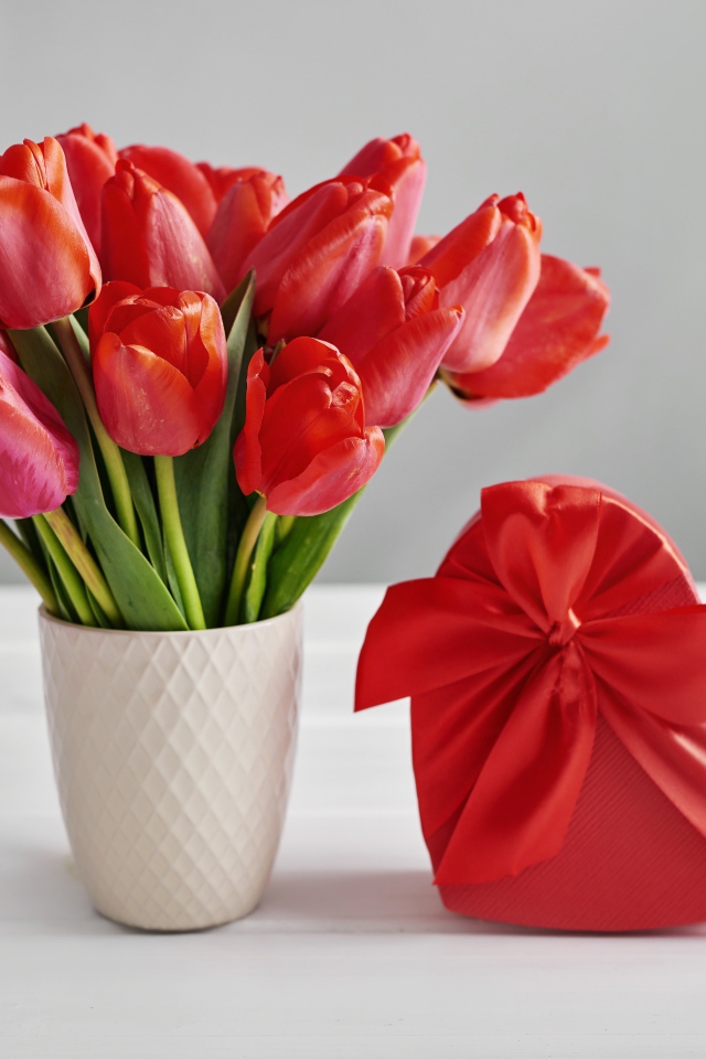 Букет красных тюльпанов на столе с коробкой в форме сердца
