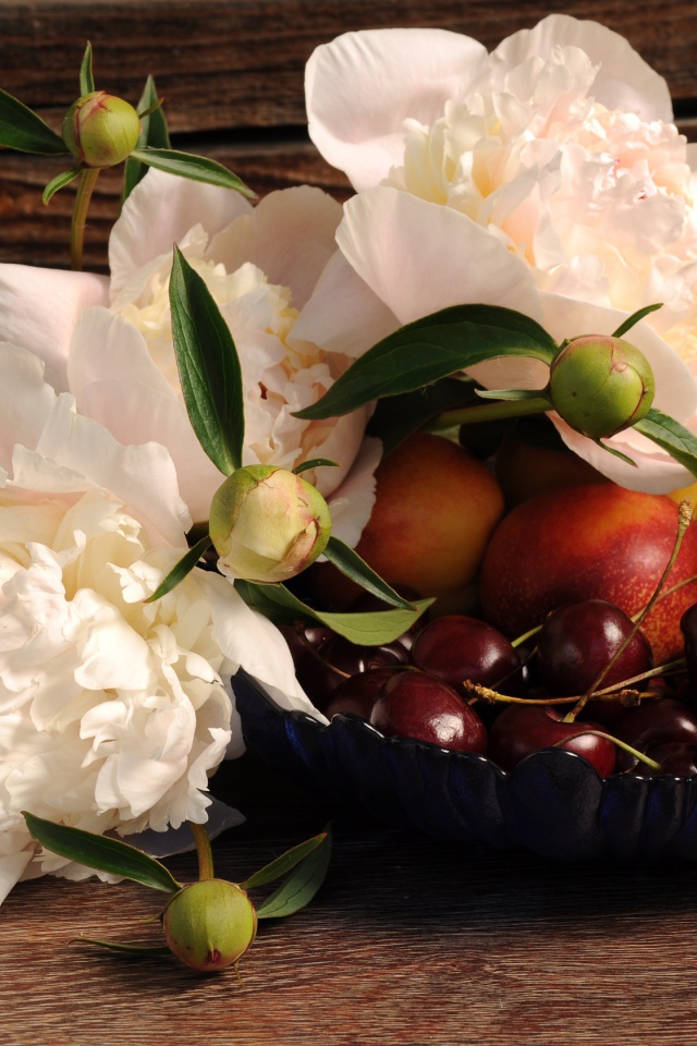 Букет белых пионов на столе с нектарином и черешней