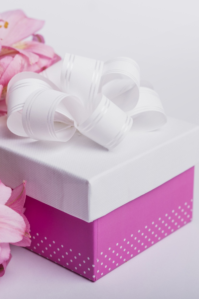 Розовые цветы альстромерии на сером фоне с подарком 