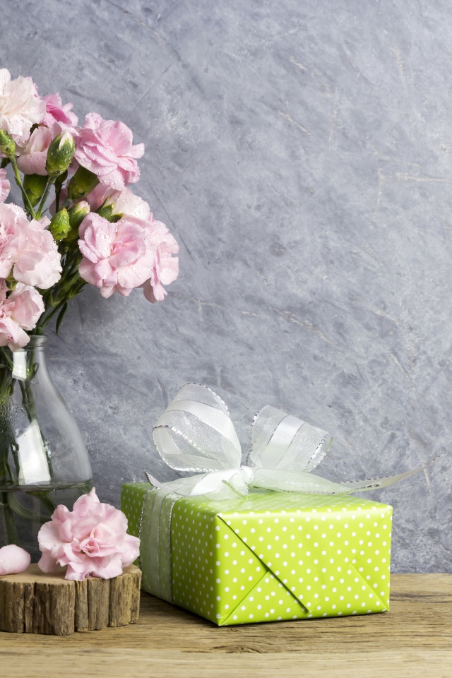 Розовые гвоздики с подарком на сером фоне