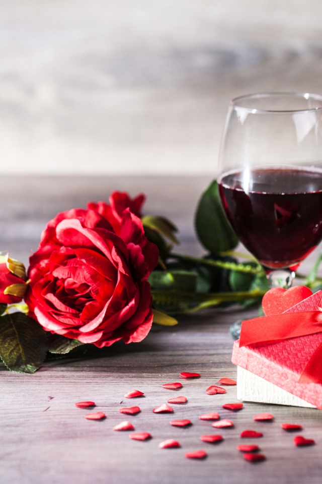 Розы, подарок и два бокала вина на столе