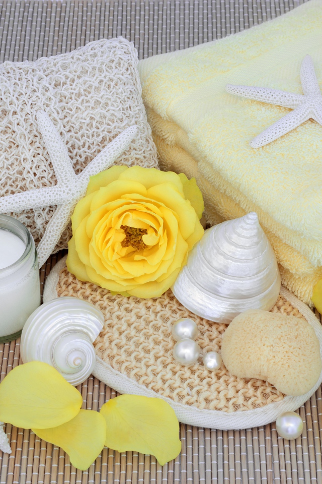 Желтые розы на столе с полотенцем, ракушками и мылом