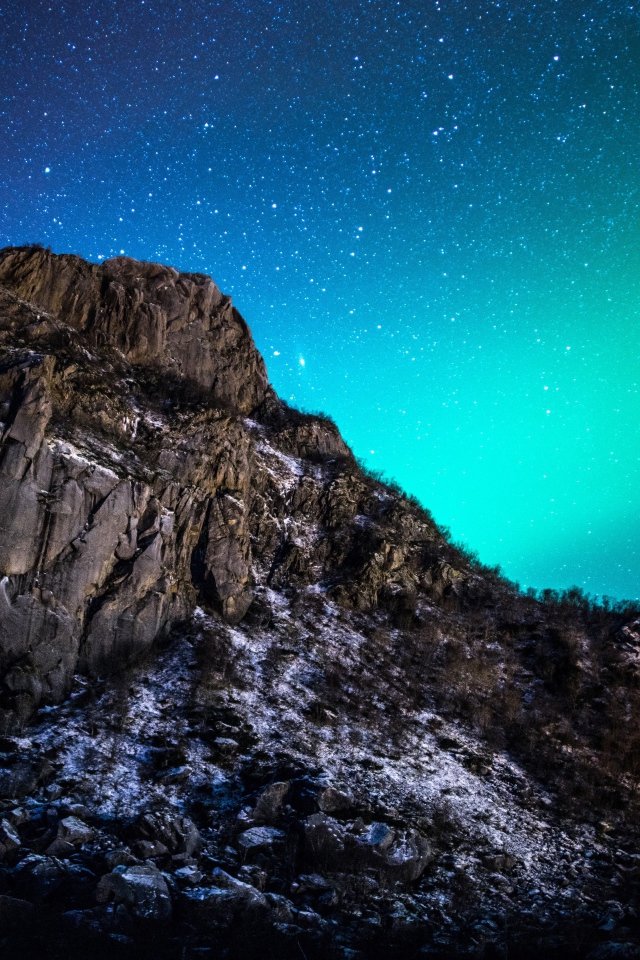 Красивое зеленое полярное сияние в звездном небе над горой 