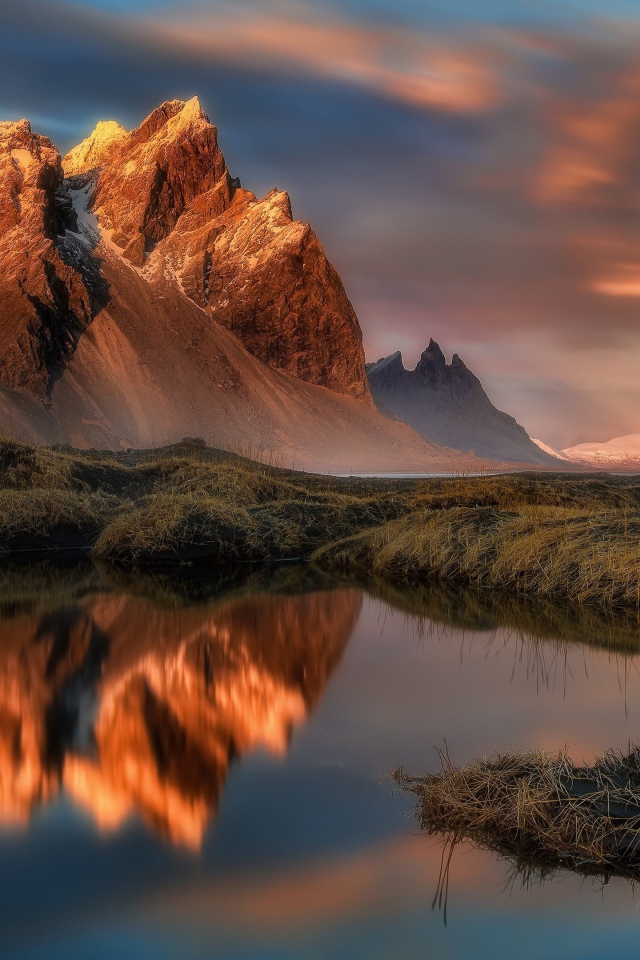 Красивое розовое небо над заснеженными горами у залива 