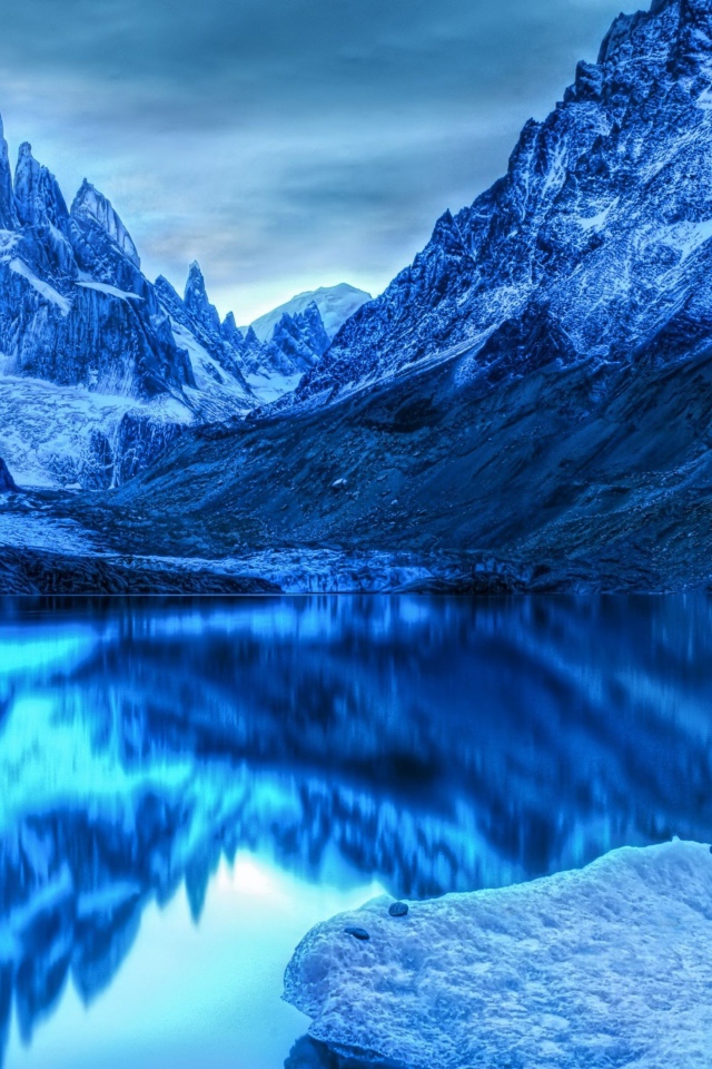 Голубой холодный закат на заснеженными горами у озера 