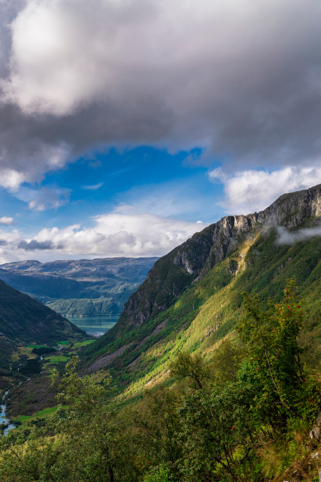 Покрытые зеленой растительностью горы под белыми облаками, Норвегия