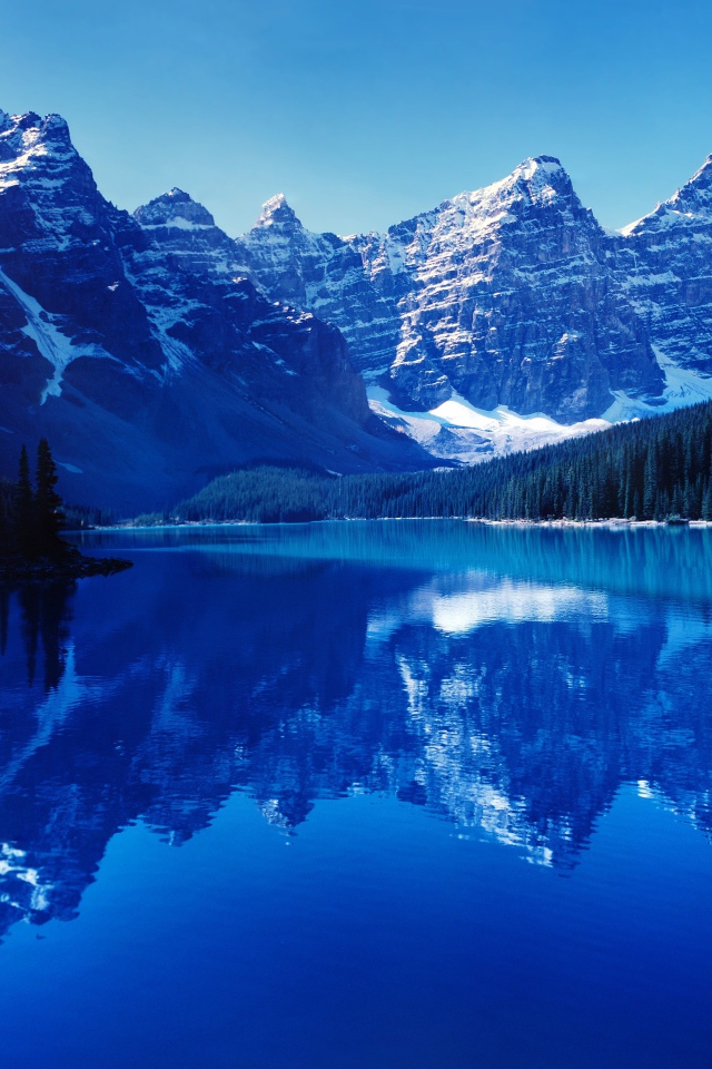 Высокие заснеженные горы отражаются в воде озера 