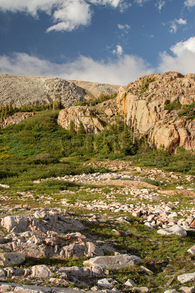 Высокие каменные горы под  голубым небом с белыми облаками