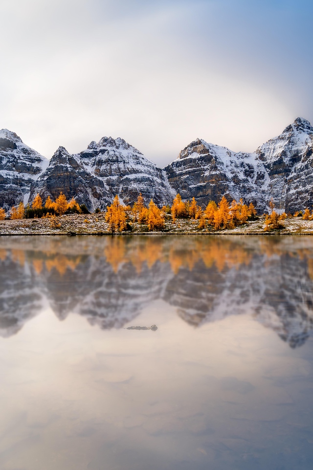 Заснеженные горы отражаются в воде озера 